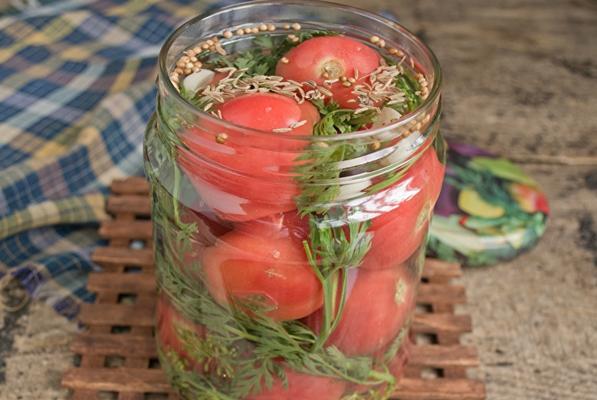 tomates avec des fanes de carottes dans un bocal sur la table